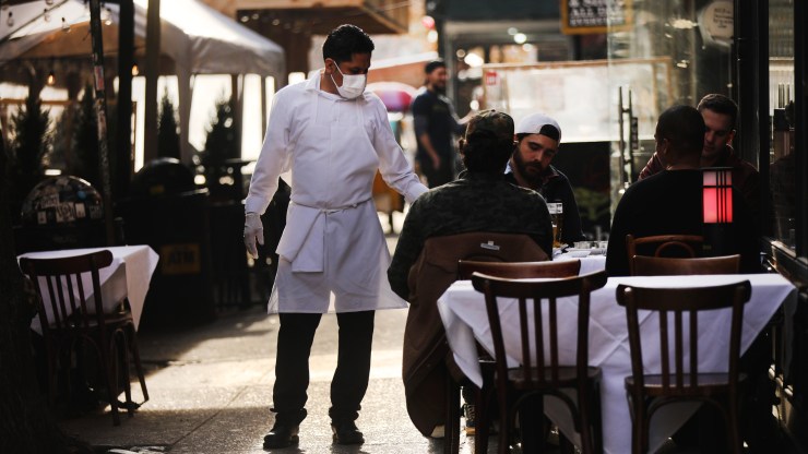 A restaurant employee moves between tables outside of a restaurant in Manhattan on Dec. 11 in New York City.