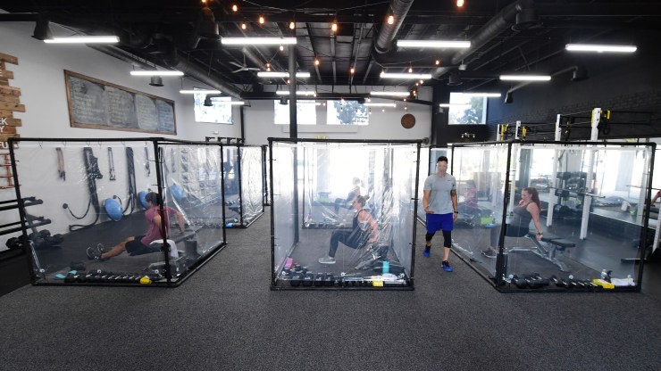 A fitness class takes place indoors with students in plastic sheet boxes in Redondo Beach, California, in June..