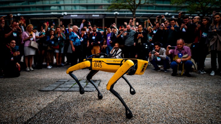 People take pictures and videos of Spot, Boston Dynamics' robot dog, during a presentation on the last day of the Web Summit in Lisbon in 2019.