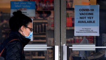 A woman walks past a "COVID-19 vaccine not yet available" sign outside a store in Arlington, Virginia.