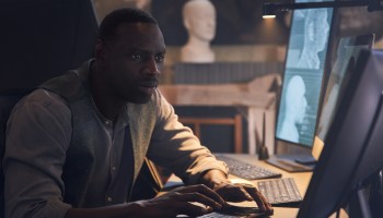 Omar Sy, who plays Assane Diop in "Lupin," studies a computer screen in this production still from the Netflix series.