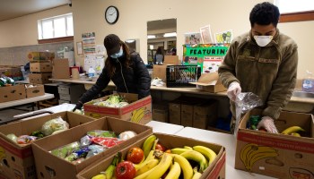 A volunteer and member of the Washington National Guard pack boxes with produce at the Nourish Pierce County food bank set up at the Mountain View Lutheran Church on April 4, 2020, in Edgewood, Washington.