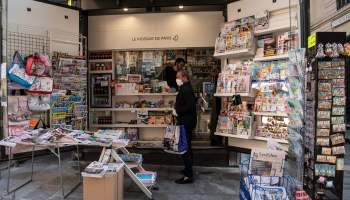 A picture taken on April 9, 2020 in Paris shows a customer buying a magazine at a newspapers kiosk.
