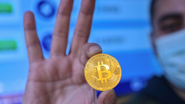 This photograph taken on December 17, 2020 shows a man holding a physical imitation of a Bitcoin at a cryptocurrency "Bitcoin Change" shop, near the Grand Bazaar, in Istanbul.