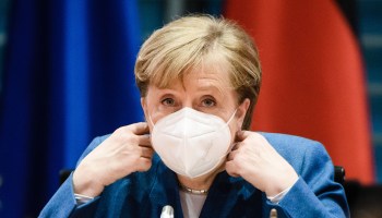 German Chancellor Angela Merkel removes her face mask as she takes a seat during the beginning of the weekly meeting of the German Federal cabinet in the conference hall of the Chancellery on January 6, 2021 in Berlin, Germany.