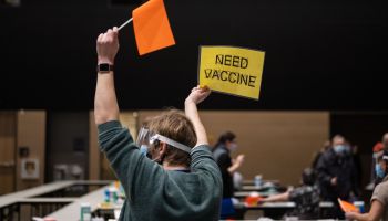 A nurse practitioner holds up a flag and a sign to call forward another patient to receive Pfizer's COVID vaccine at the Amazon Meeting Center in downtown Seattle, Washington on January 24, 2021.
