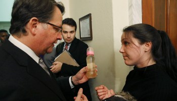 Flint resident Jessica Owens shows Sen. Gary Peters (D-MI) a baby bottle full of contaminated water, during a news conference after attending a House Oversight and Government Reform Committee hearing on the Flint, Michigan water crisis on Capitol Hill February 3, 2016 in Washington, DC.