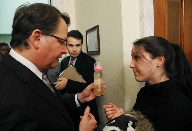Flint resident Jessica Owens shows Sen. Gary Peters (D-MI) a baby bottle full of contaminated water, during a news conference after attending a House Oversight and Government Reform Committee hearing on the Flint, Michigan water crisis on Capitol Hill February 3, 2016 in Washington, DC.