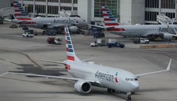 Two American Airlines planes wait at their gates as one begins to taxi. The company reported an annual net loss of $8.9 billion.