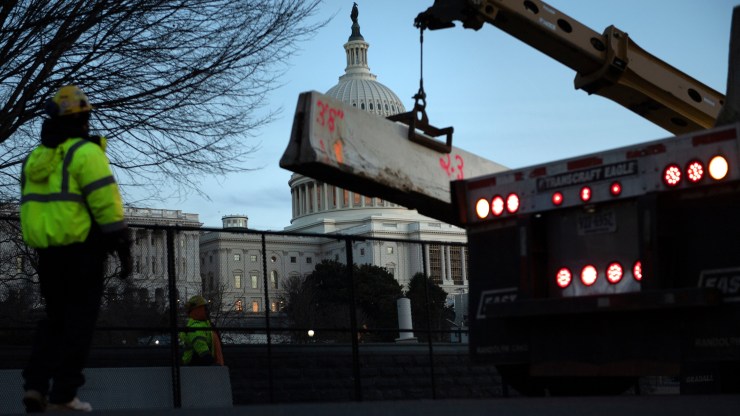Workers reinforce a crowd-control fence around Capitol Hill with concrete barriers Thursday, after a pro-Trump mob broke into the U.S. Capitol.