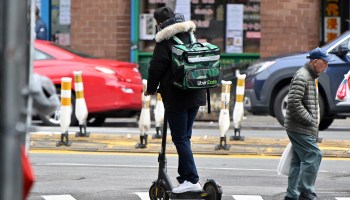 An Uber Eats delivery worker rides an electric scooter in Manhattan in 2020.
