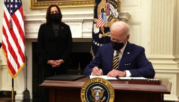 President Joe Biden signs an executive order as Vice President Kamala Harris looks on during an event on the economic crisis Friday.