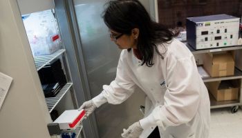 A lab worker reaches into a freezer with vaccine doses.