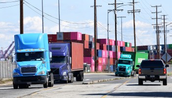 Trucks drive past stacked containers at the Port of Los Angeles. The industry is having problems recruiting and retaining enough qualified drivers.