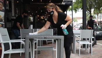 An employee wipes down outdoor tables at a restaurant in Florida.