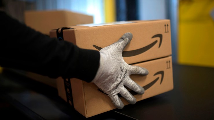 An employee carries a package at an Amazon distribution center in Germany on December 17, 2019.