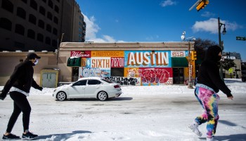Pedestrians walk on along a snow-covered street on February 15, 2021 in Austin, Texas.