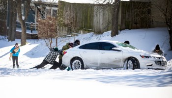People push a car out of the snow on Feb. 15 in Austin, Texas.