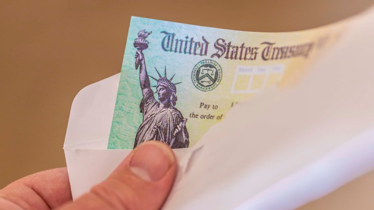 A man holds an envelope with a United States Treasury check in it.