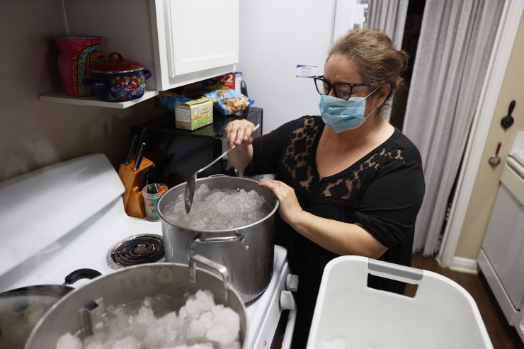 Marie Maybou melts snow on the kitchen stove on Feb. 19 in Austin, Texas. Maybou was using the water to flush the toilets in her home after the city water stopped running. Winter storm Uri brought historic cold weather, causing people to lose their water as pipes broke throughout the area.