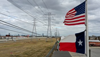 The U.S. and Texas flags fly in front of high voltage transmission towers on February 21, 2021 in Houston, Texas.