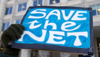 A woman holds a "Save the Net" protest sign during a demonstration against the proposed repeal of net neutrality outside the Federal Communications Commission headquarters in Washington, D.C., on December 13, 2017.