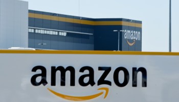 This illustration picture taken in Bretigny-sur-Orge on May 19, 2020 shows a sign with the company's logo at Amazon's center entrance as Amazon France partially reopens amid the pandemic.