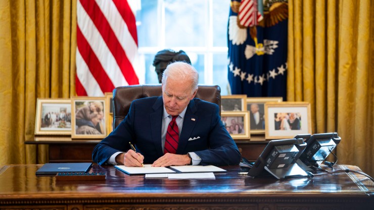 President Joe Biden signs executive orders in the Oval Office on Jan. 28, 2021.