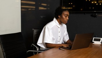 A non-binary person uses a laptop at work.