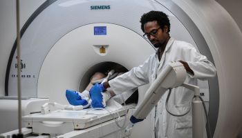 A radiologist supervises a patient undergoing a MRI.