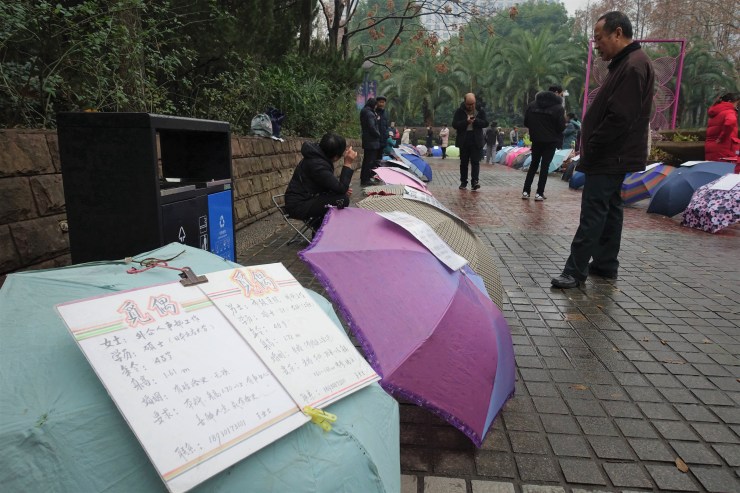 Parents at Shanghai's People's Park last year surveyed marriage adverts, which openly discloses salary and assets. (Charles Zhang/Marketplace)