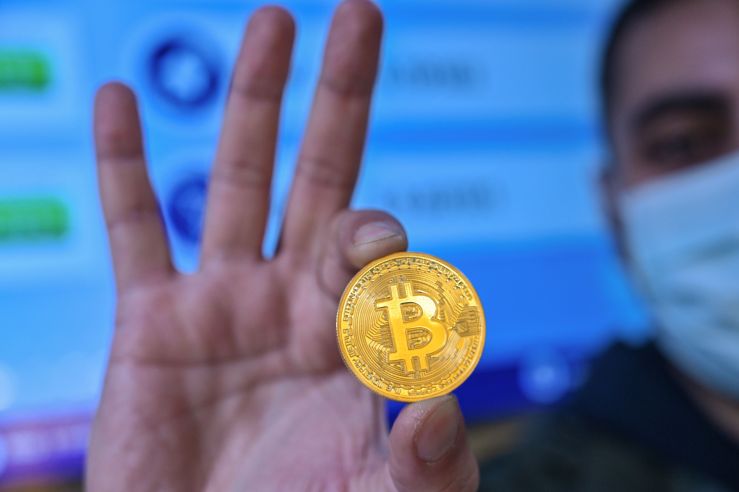 A man holding a physical representation of a bitcoin.