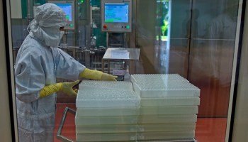 An employee in personal protective gear works on an assembly line for manufacturing vials of AstraZeneca-Oxford's vaccine at India's Serum Institute in Pune on January 22, 2021.