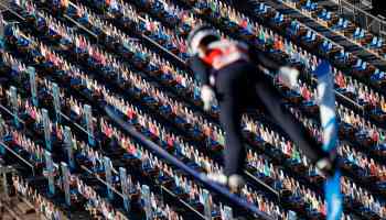 A ski jumper soars through the air above cardboard cut-outs placed in the stands to represent spectators during the trial round of the women's HS106 ski jumping event at the FIS Nordic Ski World Championships in Oberstdorf, southern Germany, on February 25, 2021.