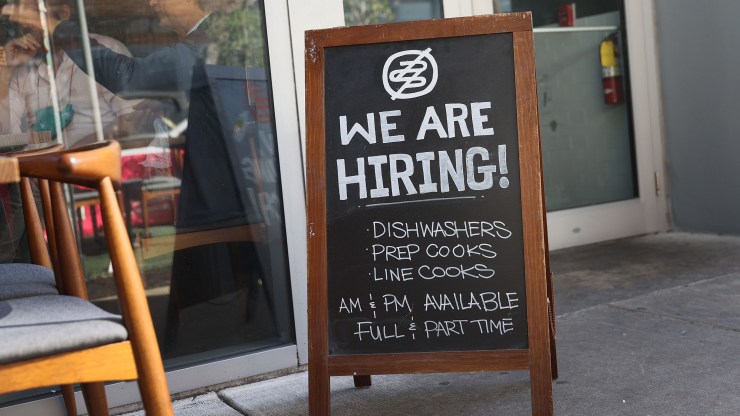A "We are hiring" sign stands in front of a restaurant in Miami, Florida.