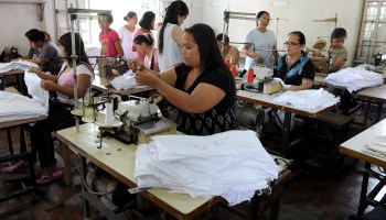 Women work at a sweatshop sewing clothes under contract with local clothing manufacturers in Manila on July 12, 2013.