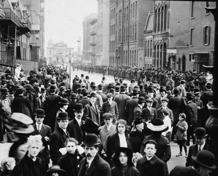 Crowds of people stand in the street, waiting to identify bodies of immigrant workers following the Triangle Shirtwaist Company fire in New York City, March 25, 1911.