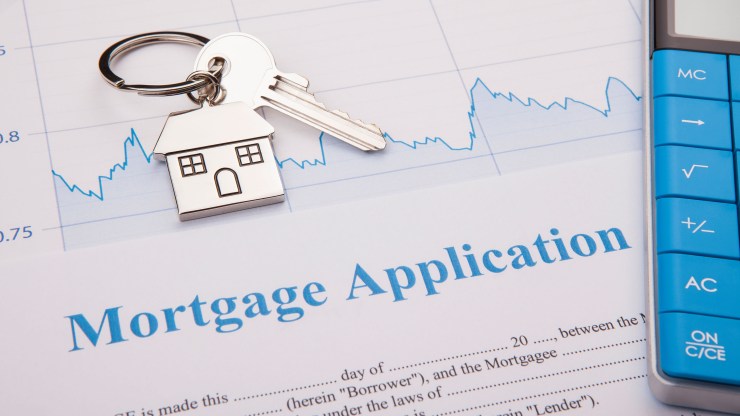 A mortgage application sits on a desk, with a property key and a calculator.