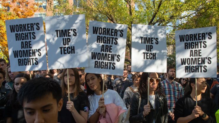 Employees stage a walkout, holding signs saying "Time's up tech" and "Worker's rights are women's rights."