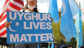 A woman holds a sign reading "Uyghur Lives Matter" at a Washington rally.