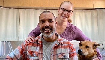 A portrait of "nomads" Hakam Salahuddin and Rebecca Bailey, and their dog, Beefy.