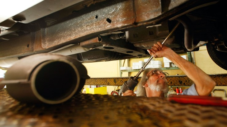 A mechanic works on replacing a truck's catalytic converter.