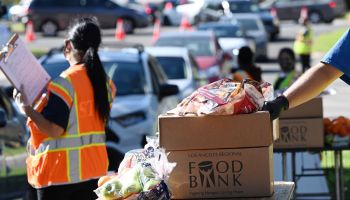 Volunteers load free groceries into cars.