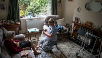 A home care worker cares for a patient in her living room.