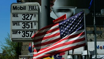 Prices posted at a gas station alongside an American flag.
