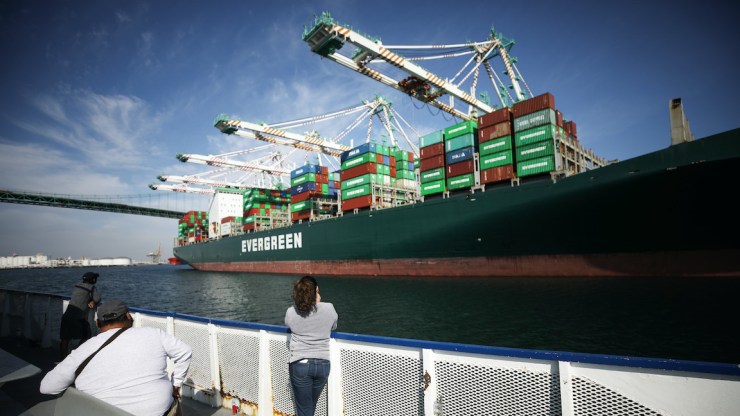 A person photographs a container ship at the Port of Los Angeles.