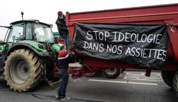 Farmers set a banner reading in French "Stop ideology in our plates" on a vehicle.