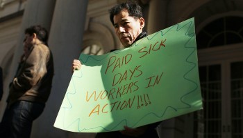 A man holds a sign reading "Paid sick days workers in action!!!!"