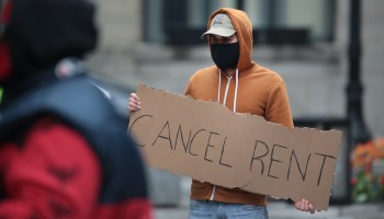A demonstrator holds a "Cancel Rent" sign.