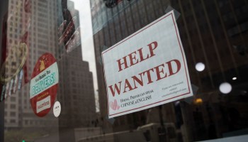 A 'help wanted sign' hangs in the window of a restaurant.